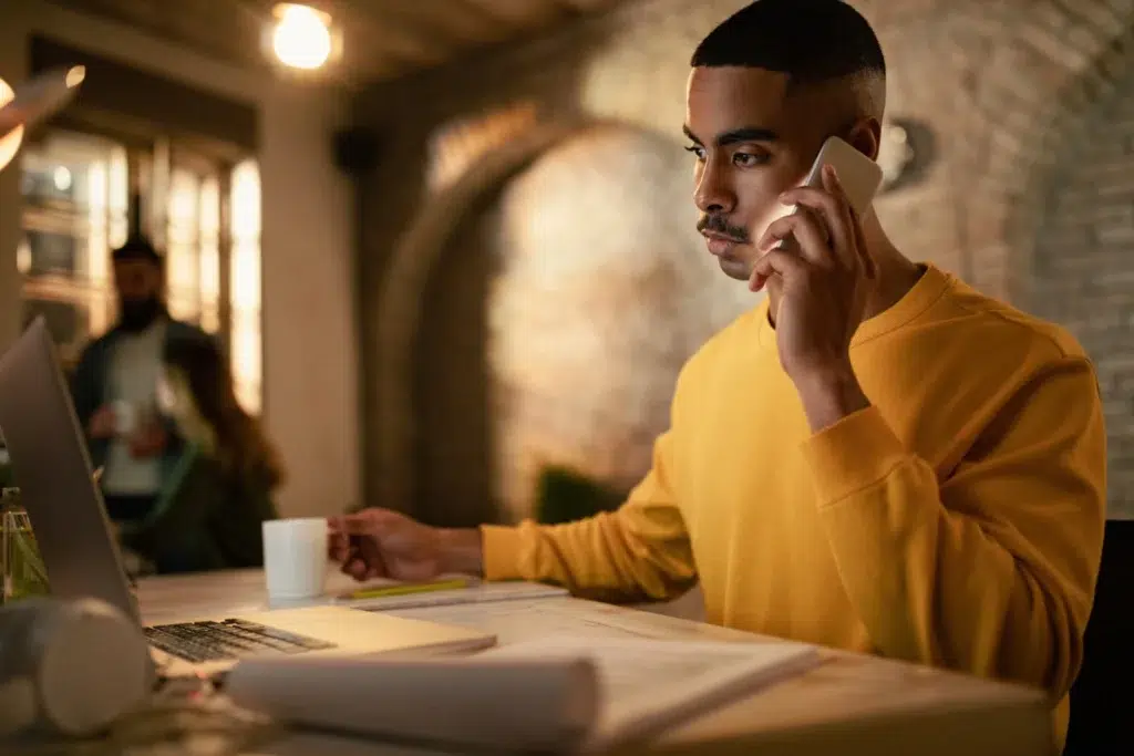 Young black entrepreneur working late computer communicating cell phone office