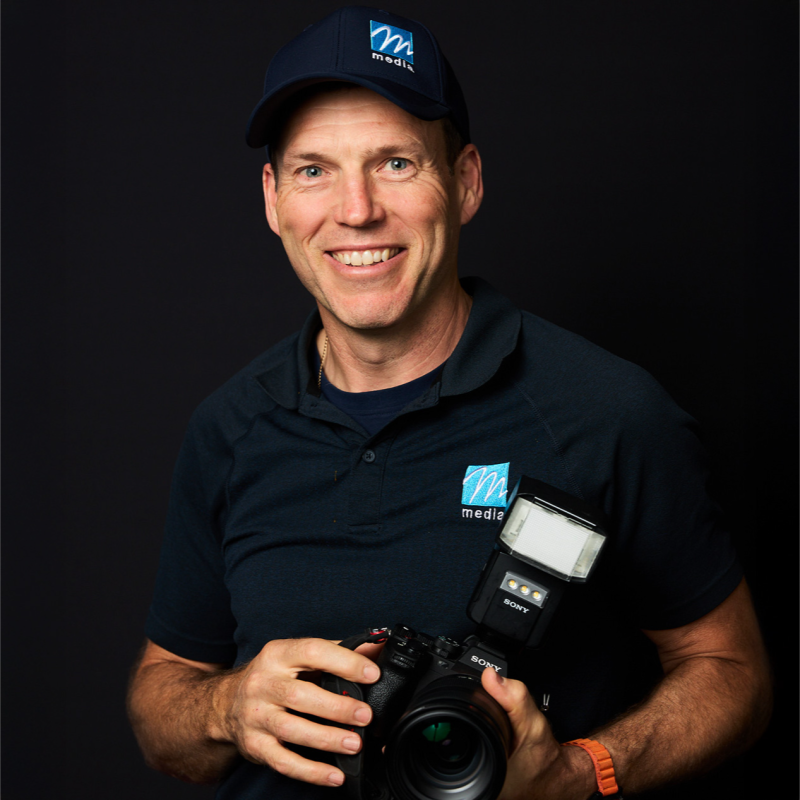 Professional headshot of Paddy McCann with a serious expression against a black background.